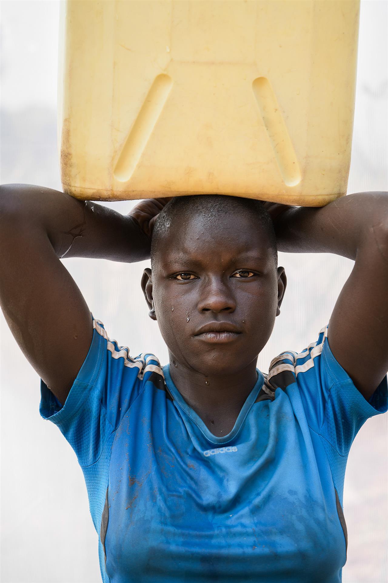 Dan Nelken: A. Sarah: Age 13. Carries a 5 gallon jerrycan of water (41lbs) home three times a day, from the series The Women of Rural Uganda, 2018
